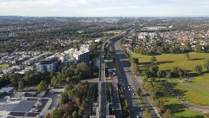 Wall Mural - Aerial drone view above Rouse Hill Station on the metro northwest railway line, Greater Sydney, NSW Australia as a train departs the station toward Kellyville in June 2024 