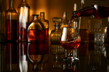 Wall Mural - Brandy is poured from a bottle into a glass.