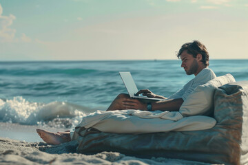 Wall Mural - Young man working with computer on the beach. Handsome man working with laptop laying on the couch at the beach.