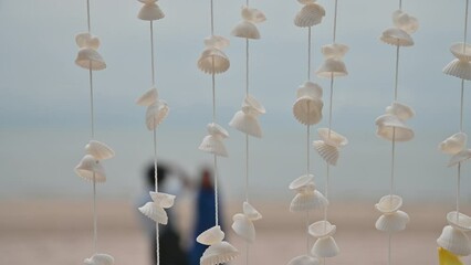 Wall Mural - Moving of Seashells mobile hanging with light wind blowing on the beach. Beautiful handicrafts produced by sea shell