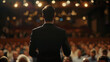© Sergei - A man stands on a stage in front of a large audience