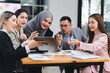 © kenchiro168 - Diverse business team actively collaborating and discussing ideas while using a tablet during an office meeting.