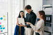 © Parichat - Young Professionals Collaborating in Modern Office with Laptop and Sticky Notes on Glass Wall, Smiling and Discussing Ideas, Bright and Airy Workspace, Teamwork and Innovation Concept