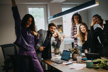 A diverse group of young professionals cheerfully celebrate a project success in a well-lit office environment, exuding teamwork and positivity.