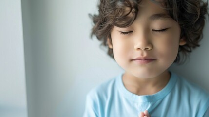 Sticker - Young child with eyes closed possibly in a state of relaxation or prayer wearing a light blue shirt with soft curly hair against a neutral background.