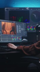 Fototapete - Female editor works in studio on computer using color grading control panel and professional video editing software. Color correction for film post production. Big screens with RGB graphic and levels.