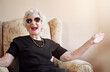 © Cecilie S/peopleimages.com - Senior, woman and happy with sunglasses in home on sofa with fun retirement, laughing and relax in living room. Elderly, person and excited with eyewear on couch in hospice with wellness and funny