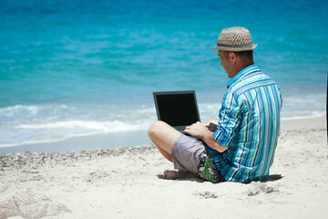 Wall Mural - A Happy man guy with laptop near the seashore weekend travel