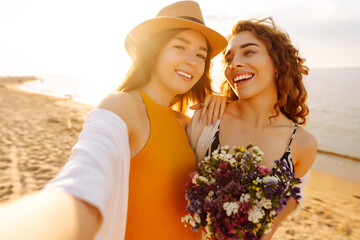 Wall Mural - Stylish pretty women on summer vacation on beach  taking selfie. Friends together. ravel, blogging, weekend, relax and lifestyle concept.