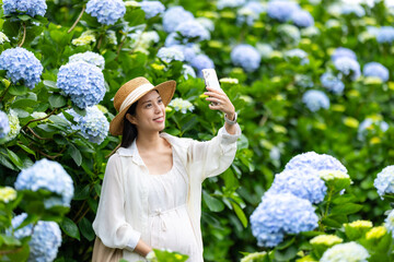 Wall Mural - Beautiful Pregnant woman take selfie on cellphone in the Hydrangea flower garden