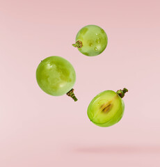 Wall Mural - Fresh green grape falling in the air isolated on pink background. High resolution image.