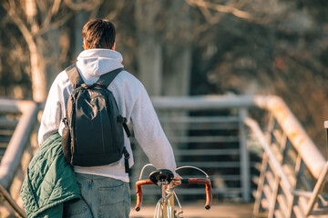 Poster - young man or student on the street with vintage bicycle at sunset with his back to him