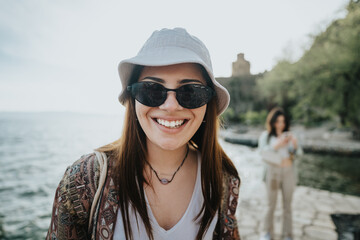 Poster - Close-up of a happy girl wearing a bucket hat and sunglasses, expressing joy by the waterfront.