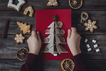 Wall Mural - Little boy holding handmade card made with recyclable natural materials, zero waste, sustainable lifestyle, hobby. Concept of christmas leisure, family time, do it yourself present.