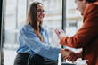 © qunica.com - Two business colleagues happily greeting each other with a handshake in an office environment showcasing professionalism and positive interaction.
