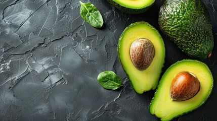 Sliced avocados oil placed on stone surface among green leaves, top view gray table whole avocado