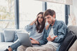 © Daniel - Millennial couple annoyed by stuck laptop or online news sitting together on sofa, frustrated young angry customers confused by computer problem feeling perplexed or puzzled about email message.