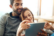 © peopleimages.com - Happy, couple and hug with tablet and web app subscription for streaming, movie selection or tv choice. Smile, man and woman with tech and love embrace on couch for bonding, search and scroll at home