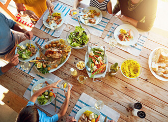 Table, food and above of family for lunch, supper and eating meal at home together. Celebration, parents and children with dish for bonding, relax and talking for nutrition, health and wellness