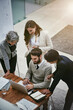 © peopleimages.com - Above, laptop and business people in office for project, planning and documents in modern agency. Team, collaboration and tech in workplace for support, partnership and brainstorming for strategy