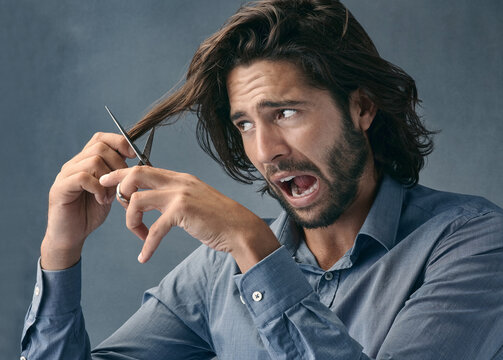 Trimming, hair and scared man with scissors for grooming, facial cleaning and mistake on grey studio background. Barber, fail and face of fear model cutting hair for comedy cosmetic beauty look