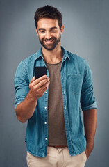 Poster - Cellphone, smile and read with man in studio, communication and social media on gray background. Internet, online and scroll for texting on dating app, talk or happy male person on mobile for love