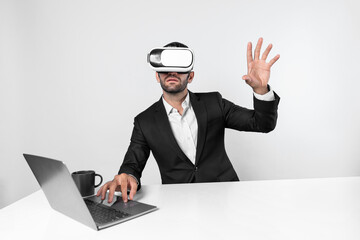 Skilled business man looking at data analysis while sitting at table with laptop and wearing VR glasses. Project manager working by using virtual reality system or connecting at metaverse. Deviation.