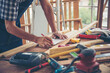 © aFotostock - DIY craftsperson asian man working wood heap carpenter objects woodwork desk. Architect man hands use ruler measure hammer home improvement. Wooden builder carpenter repairing construction workshop