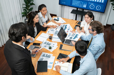 Diverse group of business analyst team analyzing financial data report. Finance data analysis chart and graph dashboard show on TV screen in meeting room for strategic marketing planning. Habiliment