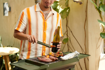 Wall Mural - Cropped image of smiling man drinking wine when grilling food in backyard