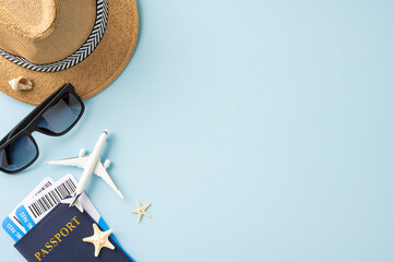 Flat lay of summer travel essentials including a straw hat, passport, boarding pass, sunglasses, and a model airplane on a blue background