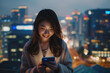© Bank-adtapon - Urban lifestyle portrait of a happy Asian woman using her smartphone with a city skyline in the background at night ,generative ai