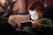 © Halfpoint - Cute boy sitting on bed watching something on smartphone. Children's screen time.