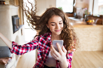 Wall Mural - University student sitting at home on the floor scrolling on smartphone.