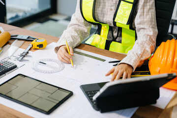 Wall Mural - businessman hand working and laptop with on on architectural project at construction site