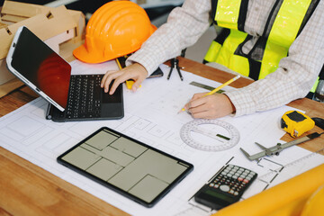 Wall Mural - businessman hand working and laptop with on on architectural project at construction site