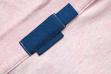 Wall Mural - Blank blue laundry care clothes label on pink shirt fabric texture background