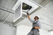 © Serhii - African American electrician repairing air conditioner indoors