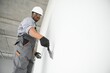© Serhii - African american Plasterer in working uniform plastering the wall indoors