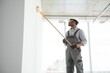 © Serhii - African man paints a white wall with a roller. Repair of the interior
