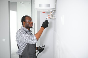 Young African Male Plumber Repairing Boiler