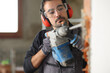 © Antonioguillem - Construction worker is wrecking wall using rotary hammer