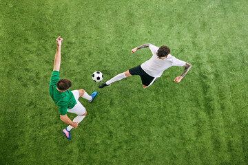 Wall Mural - Aerial view. Two football athletes, one in white swings his leg, and other in green braces for play on lush playground. Concept of professional sport, championship, final match, movement. Ad