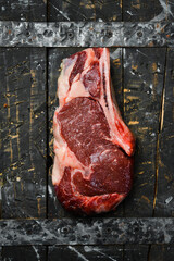 Wall Mural - raw cowboy steak with seasonings on a wooden board, prime rib eye on bone, top view. Top view.