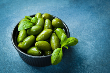 Wall Mural - Green pickled pitted olives in a black stone bowl. On a dark concrete canvas.