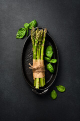 Wall Mural - A black stone bowl with a bunch of fresh asparagus. Top view.