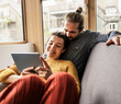 © Westend61 - Young boyfriend and girlfriend watching tablet PC on sofa at home