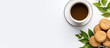 © HN Works - Flat lay copy space image of an office workspace setting on a white background consisting of a cup of coffee laptop biscuit green leaf notebook and pen Top view