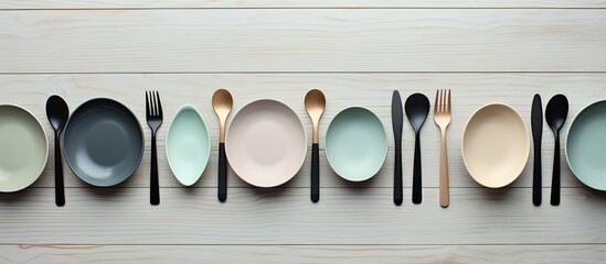 Aufkleber - A minimal and elegant flat lay view of a gray wooden background featuring a beautiful collection of empty pastel plastic tableware bowls spoons knives and forks Perfect for copy space images