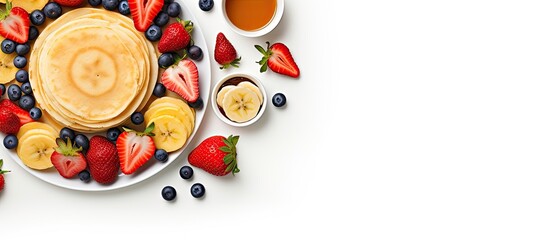 Wall Mural - Top view of a summer breakfast consisting of delicious pancakes adorned with fresh fruits like banana blueberries and strawberries The copy space image features a white background creating an invitin